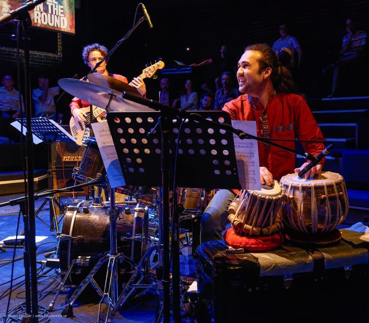 Table and guitar players performing in the round
